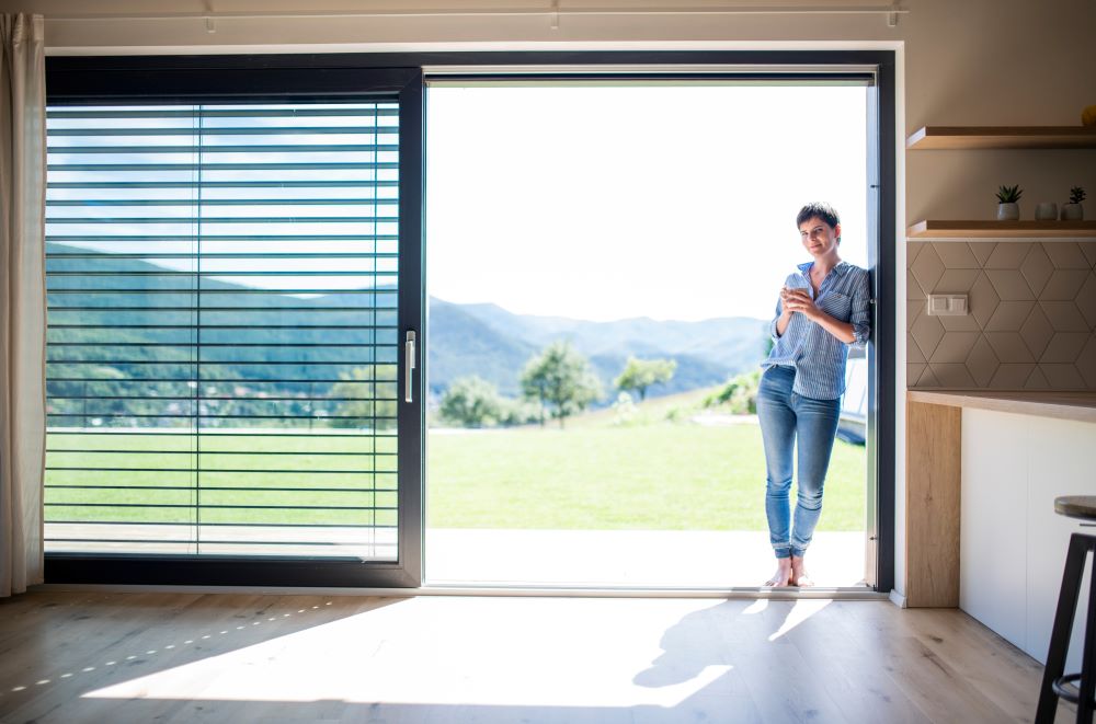woman standing in large sliding door with lovely view of mountains after building a house in colorado