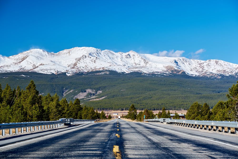 road leading to snow-capped peaks where a could would be building a house in colorado